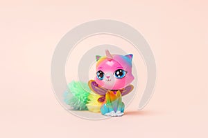 Toy for a little girl. Toy fantasy plastic multi-colored cat with a horn and butterfly wings on a pink background