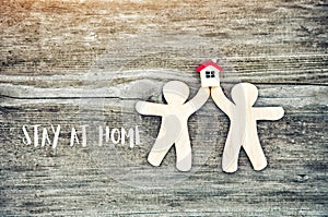 Toy little men holding house model with Stay at home text.