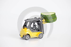 A toy loader or construction crane in bright yellow carries a piece of cucumber and a piece of black freshly baked bread. Close-up