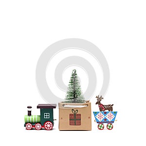 A toy locomotive carries a Christmas tree in a gift bag. Feast of Christmas. Isolated photo for design.