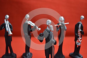 Toy Man with microphone and musicians on red background.