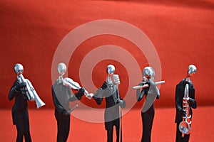 Toy Man with microphone and musicians on red background.