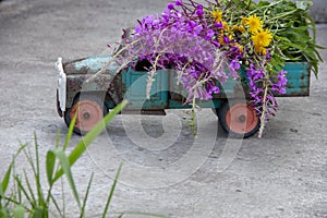 toy metal machine with traces of corrosion. Rust on the machine's gland. Flowers of fireweed by car