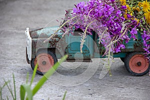 toy metal machine with traces of corrosion. Rust on the machine's gland. Flowers of fireweed by car