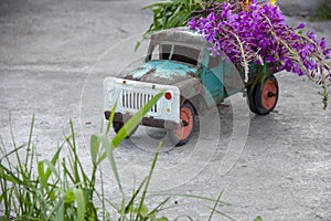 toy metal machine with traces of corrosion. Rust on the machine's gland. Flowers of fireweed by car