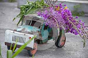 toy metal machine with traces of corrosion. Rust on the machine's gland. Flowers of fireweed by car