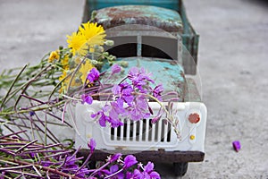 toy metal machine with traces of corrosion. Rust on the machine's gland. Flowers of fireweed by car