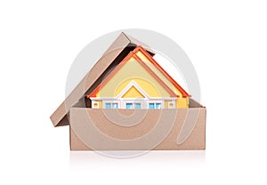 Toy model of a house in a cardboard box on white background.