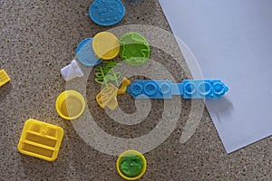 Toy molds for use with yellow and green blue plasticine. Children toys on the floor with green clay