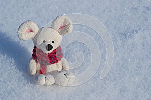 Toy mouse a symbol of the Chinese New Year. In a red knitted scarf. Against the background of white snow. Space for text