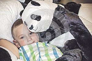 A toy panda hugs a boy with wet eyes. A porter of a child who is crying in a toy store.