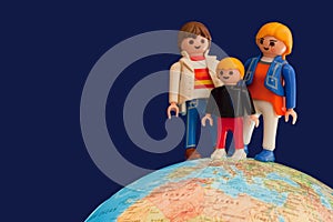 Toy parents and child standing on globe