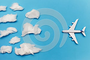 Toy plane on blue background flies to overcast. Flat lay of bad weather and transportation and travel concept