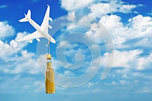 Toy plane and a bottle of whiskey on a background of sky with clouds. Concept on the topic of alcohol abuse on board an airplane