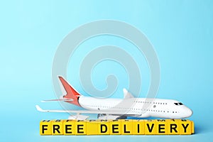 Toy plane and cubes with words FREE DELIVERY on blue background, space for text. Logistics and wholesale concept