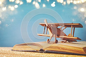 Toy plane and the open book on wooden table. glitter overlay