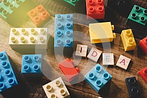 Toy plastic bricks on wooden table with alphabet tiles word IDEA