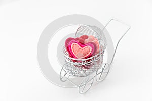 Toy pram with wool heart on white background. Valentine's Day or Newborn Greeting Card.