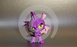 The toy is a purple dragon with yellow eyes