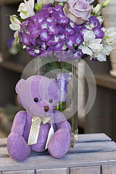 Toy purple Teddy bear sitting on a wooden box