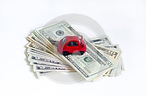 Toy red car and a stack of money dollar bills American dollars on a white isolated background. buy a car on credit.