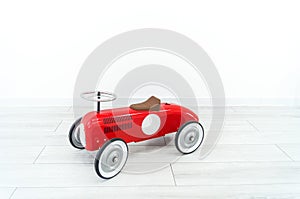 Toy red retro car. The child plays with transport