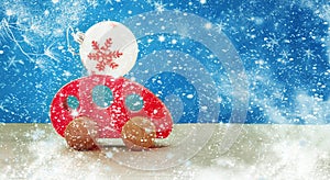 Toy red wooden car carries a Christmas ball. Merry Christmas and New Year holiday background