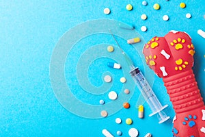 Toy rubber bone for dogs and many colored tabbies with syringe on blue background. The concept of a vetenary clinic for pets