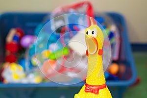 Toy rubber shriek yellow chicken on blur toy background in messy