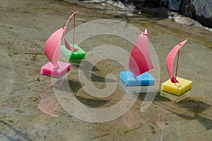 Toy sailboats made from kitchen sponges. Children`s sailing regatta in the city fountain. Four children`s colorful ships are