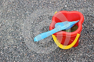 Toy sand pails and shovels over a gray small stones background