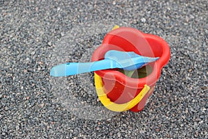 Toy sand pails and shovels over a gray small stones background