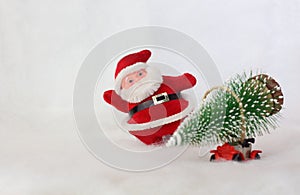 Toy Santa Claus on background blurred toy car carrying Christmas tree. Simulated snowy landscape. Space for text.