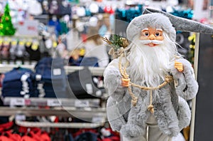 Toy Santa Claus in a gray coat on the background of a clothing store