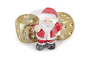 A toy Santa Claus is standing near two golden dice and greets you / isolated on white.