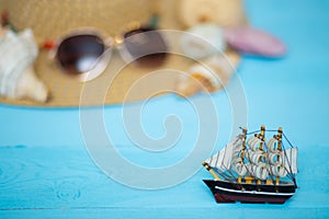 Toy ship, blurred hat, sunglasses and shells on back