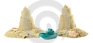 Toy ship between two castles made of sand isolated on white. Beautiful lighthouses