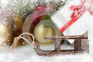 Toy sleigh and Christmas decorations as background, decorated with snow