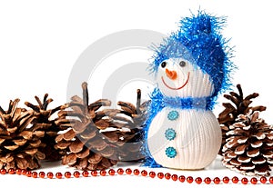 Toy snowman in blue hat and scarf with pine cones isolated on white background