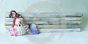 Toy snowman, caramel stick, Christmas decorations on a light wooden background