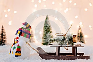 Toy snowman pulling small wooden sleigh