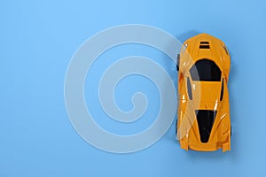 Toy sports yellow car on a blue background, top view. Copyspace for your text