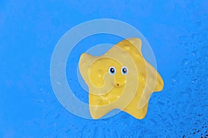 Yellow toy starfish on blue surface background