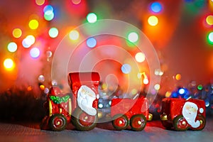 Toy Steam Train with Santa Claus on a background of golden garlands and blur of colored lights