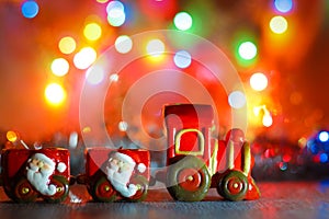 Toy Steam Train with Santa Claus on a background of golden garlands and blur of colored lights