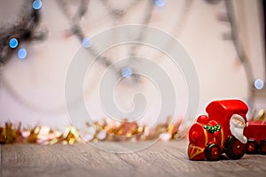 Toy Steam Train with Santa Claus on a background of golden garlands and blur of colored lights