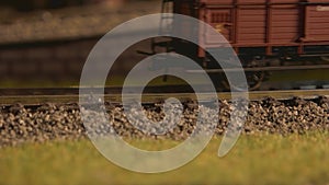 Toy steam train with wagons moving on railroad.