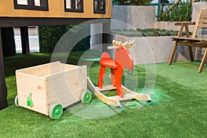 Toy storage with wheels and a red rocking horse on the artificial grass