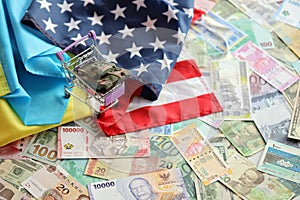 Toy tank on US flag and ukrainian flag on many banknotes of different currency