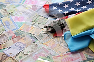 Toy tank on US flag and ukrainian flag on many banknotes of different currency
